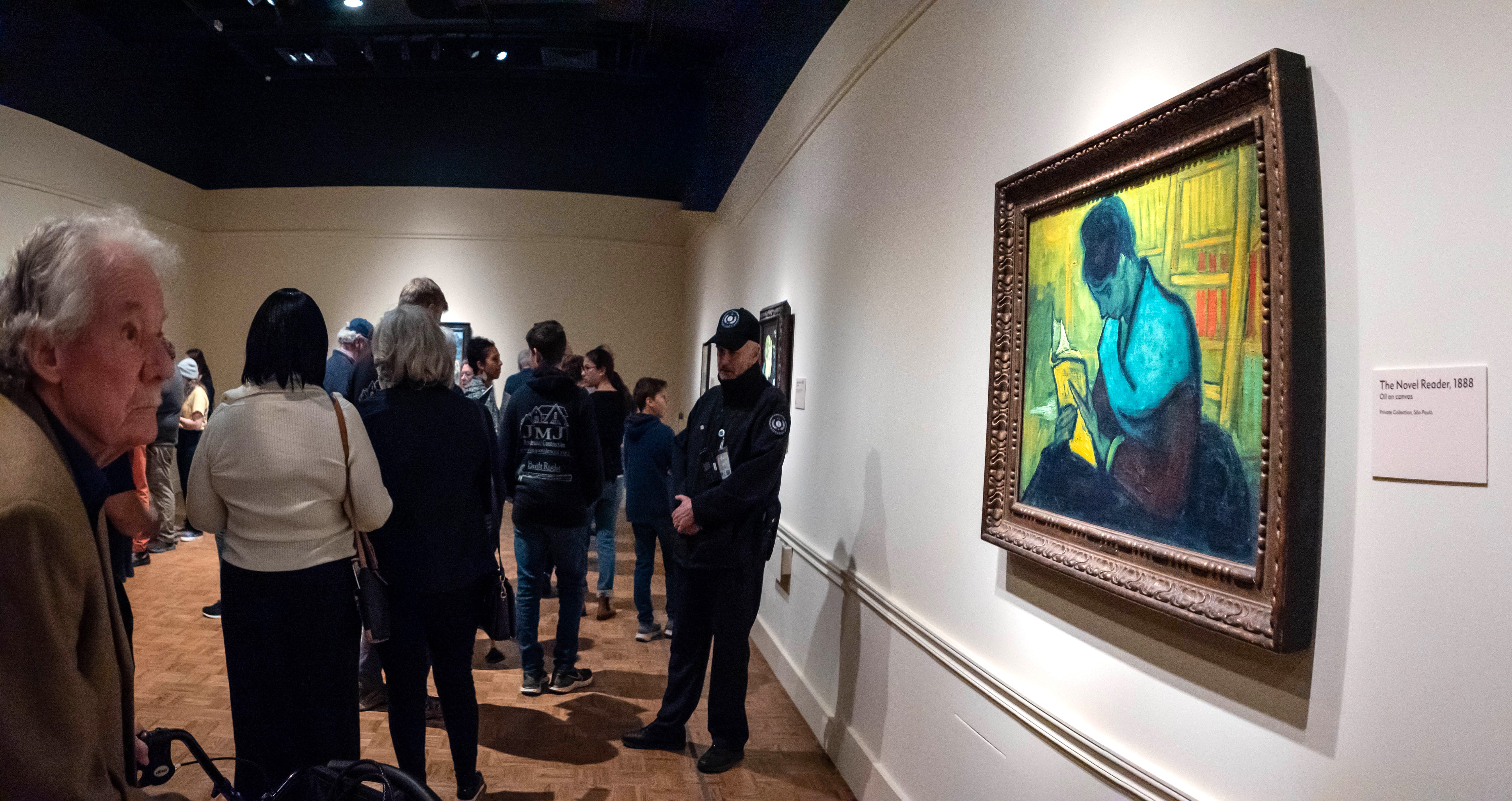 Visitors file past at the Van Gogh painting "Liseuse De Romans"  also known as "The Novel Reader", as a security guard stands near the painting, during the Van Gogh in America exhibit at the Detroit institute of Arts, Wednesday, Jan. 11, 2023. Brazilian art collector Gustavo Soter's art brokerage company, Brokerarte Capital Partners LLC, sued the DIA, describing an international hunt for a rare oil painting by the Dutch Post-Impressionist master.