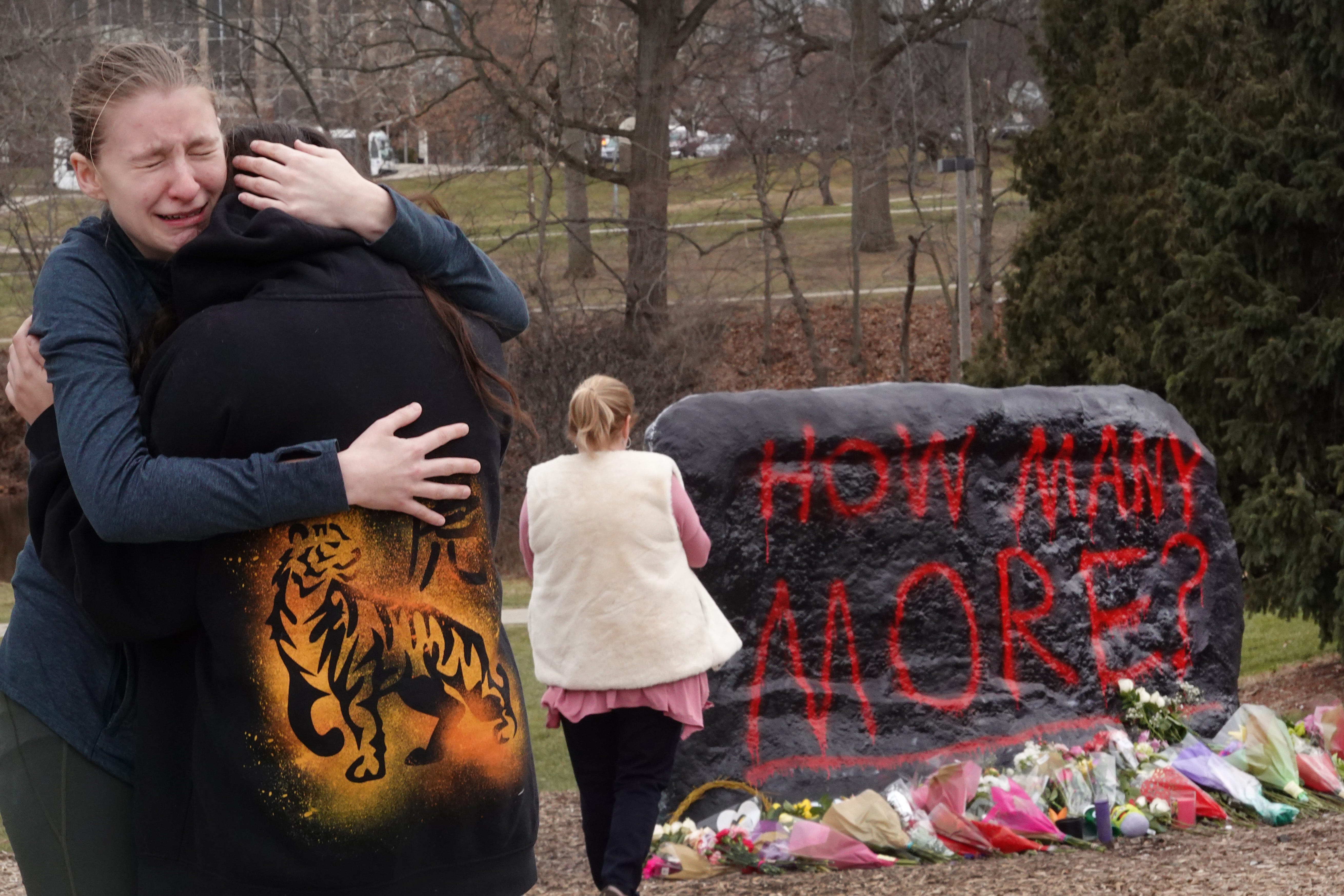 People leave flowers, hug and pray at a makeshift memorial at "The Rock" on the campus of Michigan State University on February 14, 2023 in Lansing, Michigan.