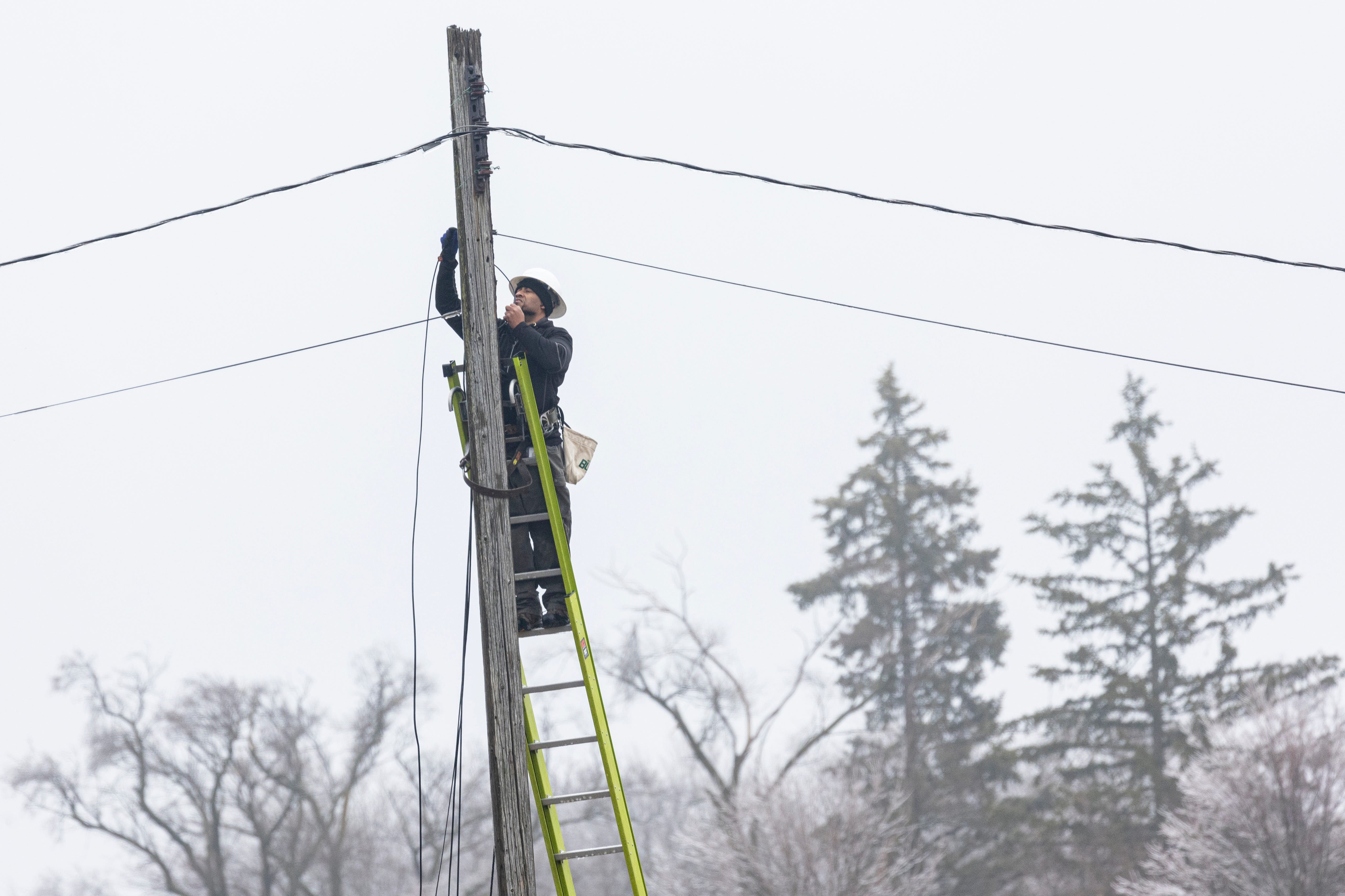 An Xfinity worker repairs a cable following an ice storm in Paw Paw, in Van Buren County, Michigan, Thursday.