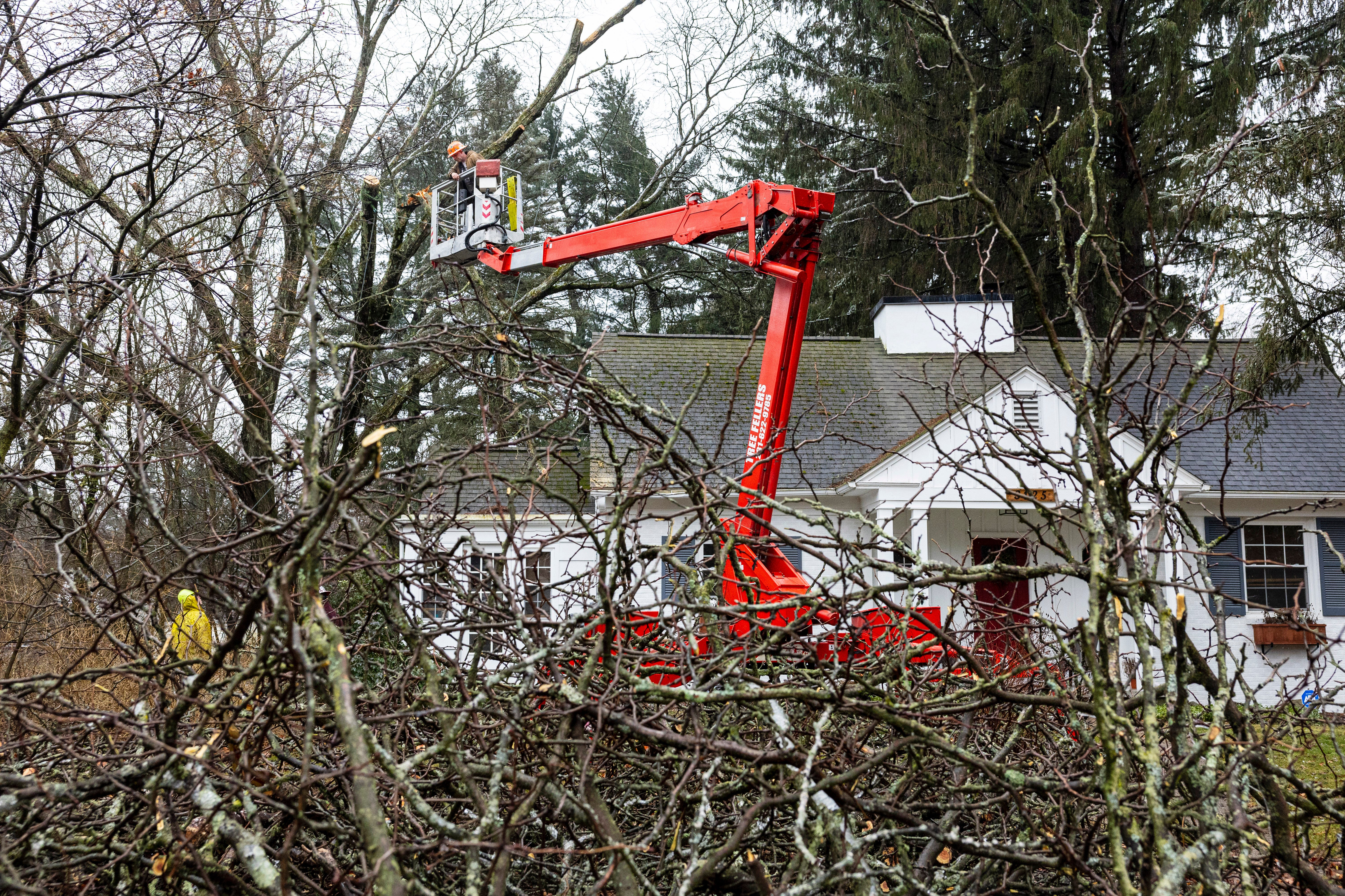 Crews remove a tree dangling over the roof of a home in the Winchell neighborhood following an ice storm in Kalamazoo