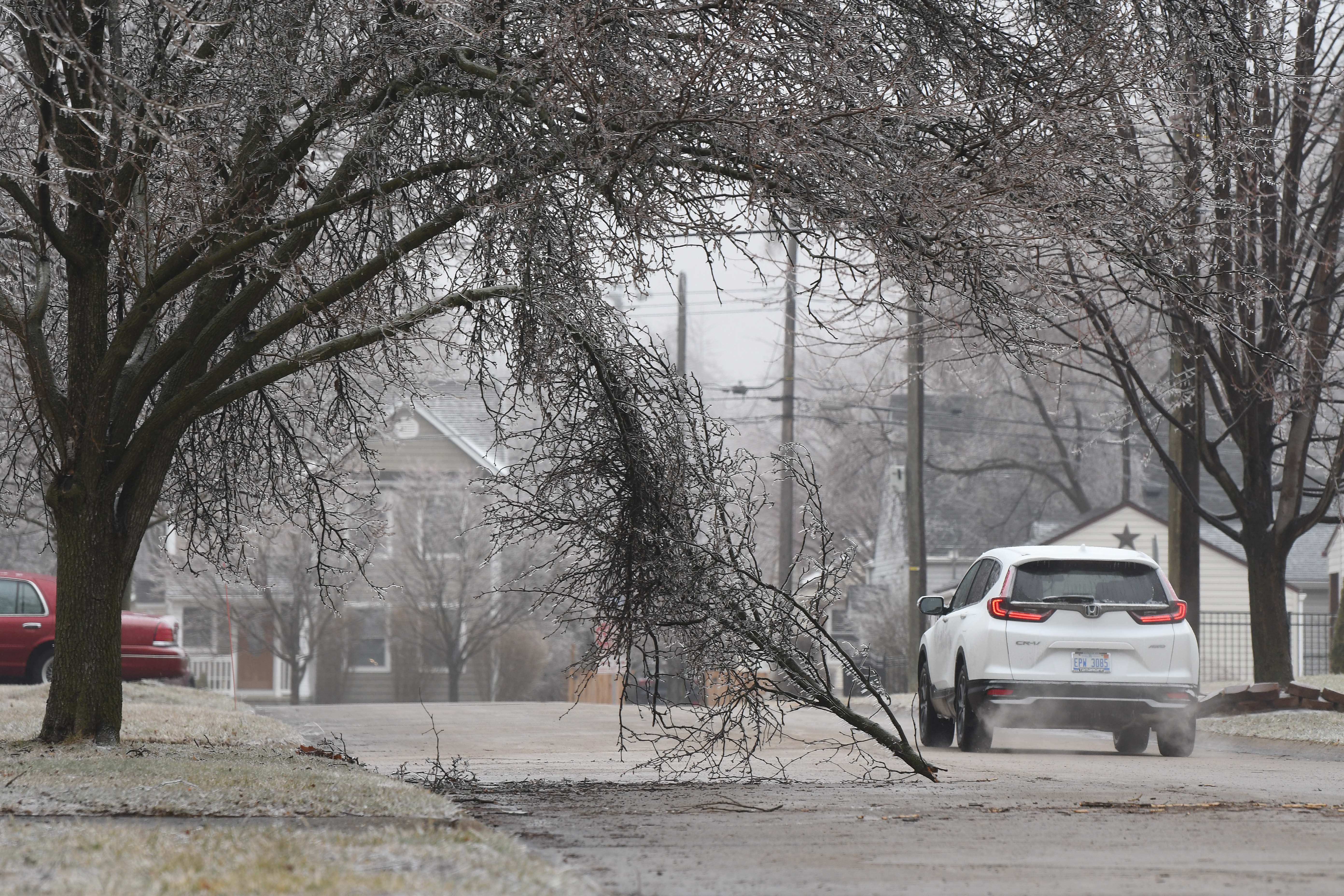 A car goes around a fallen branch on Henley due to an over night ice storm in Berkley, Michigan on February 23, 2023.
