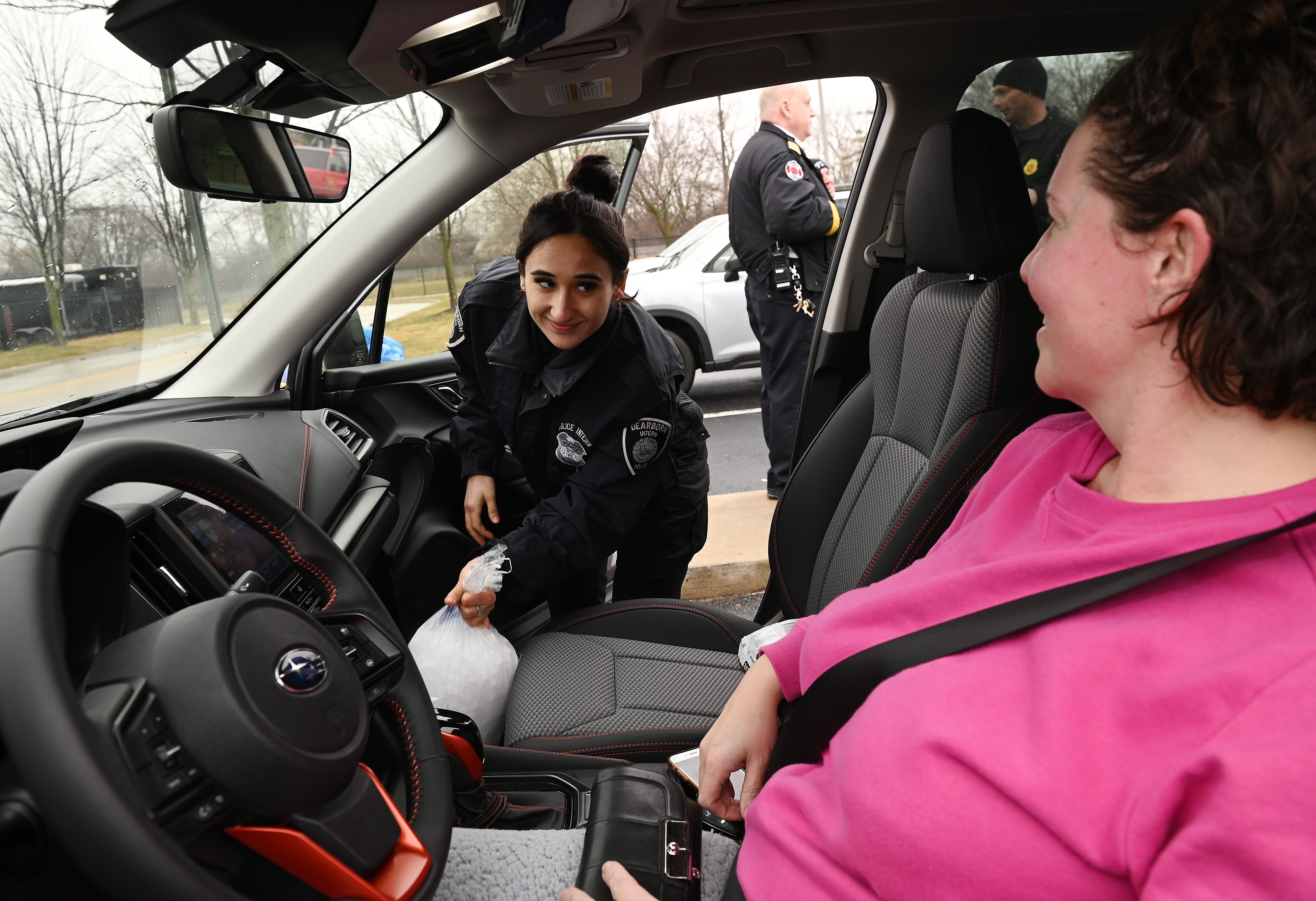 L-r, Dalal Abuhassan, 21, Police Intern of the City of Dearborn delivers two bags of dry ice to Jennifer Miller, 45, of Dearborn, during the free give away by the City of Dearborn to help residents affected by the ice storm. February 23, 2023, Dearborn, MI.