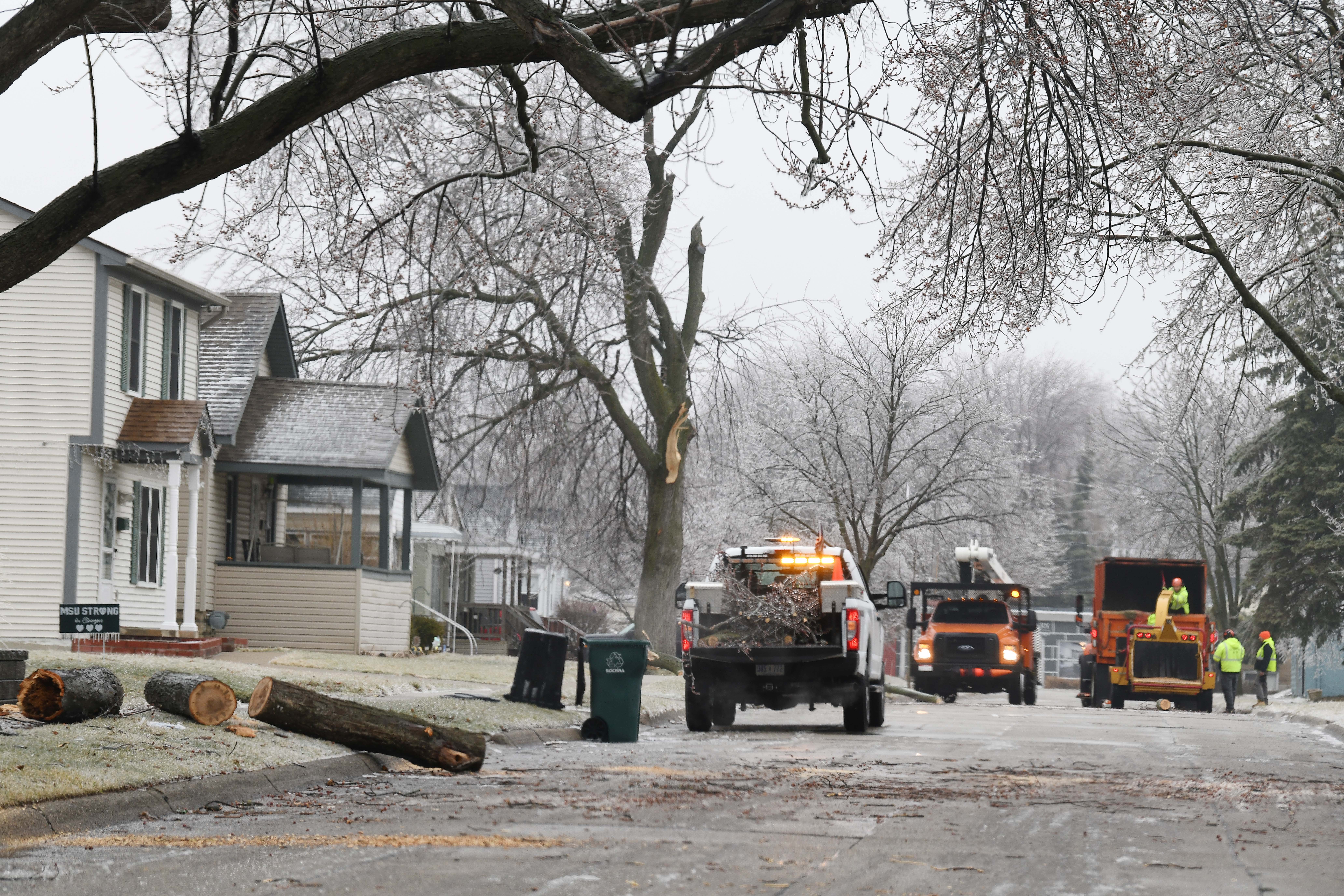 Work crews clear downed tree limbs on Nakota in Royal Oak from the overnight ce storm in Royal Oak, Michigan on February 23, 2023.
