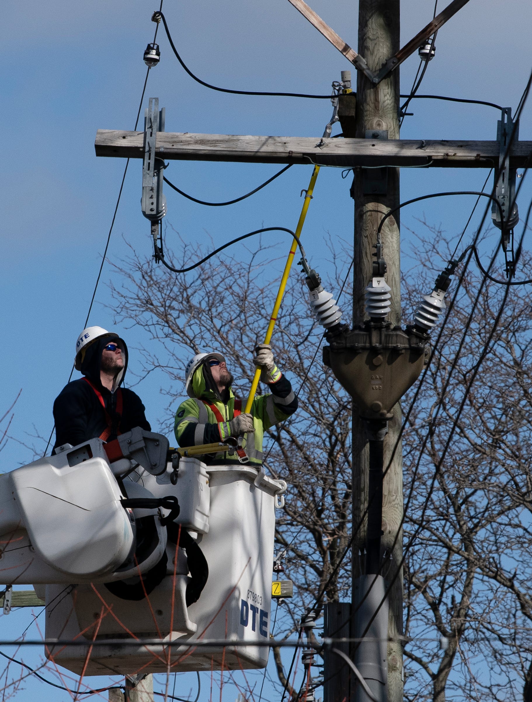 DTE servicemen work to restore electricity to a neighborhood in Grosse Pointe Farms Friday afternoon, February 24, 2023,  after a midweek winter storm coated the area with freezing rain knocking out power to thousands of homes and businesses.